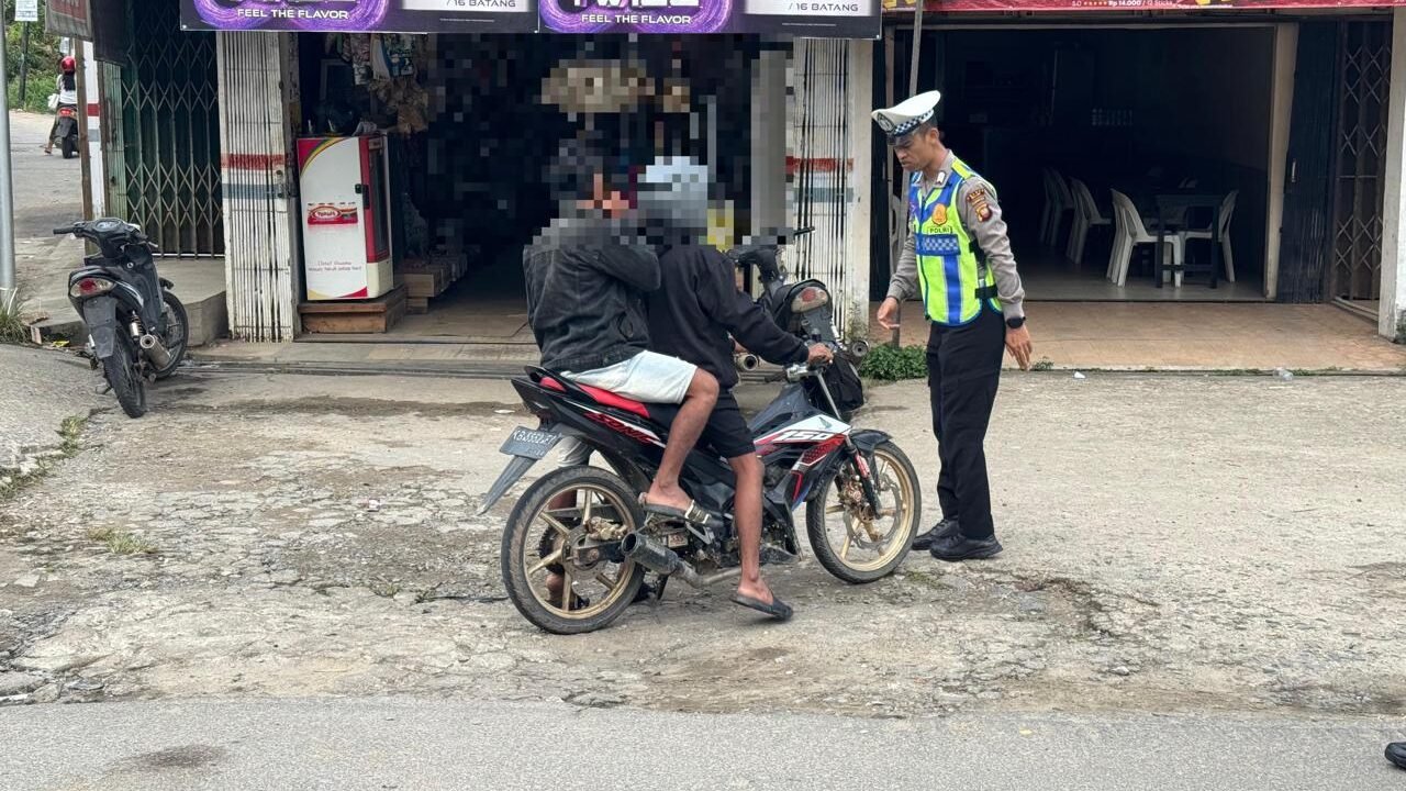 Personel kepolisian lalu lintas memberikan teguran dan penindakan kepada pengendara sepeda motor yang melanggar aturan kelengkapan berkendara di jalan raya.