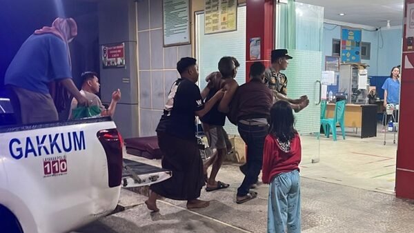 Personel kepolisian saat membantu proses evakuasi medis darurat seorang pasien lansia menuju ruang IGD rumah sakit menggunakan armada mobil patroli.